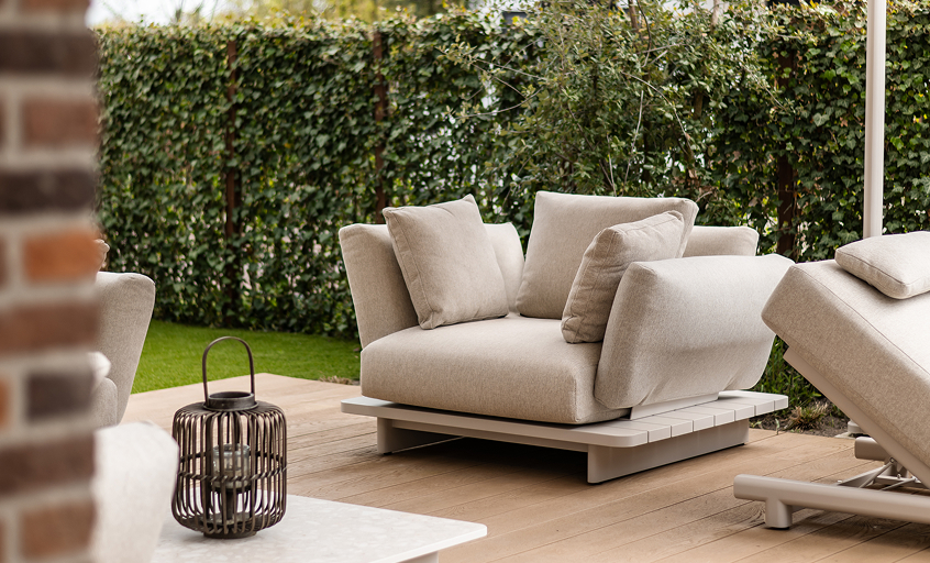 Beige outdoor lounge chair on wooden terrace surrounded with greenery