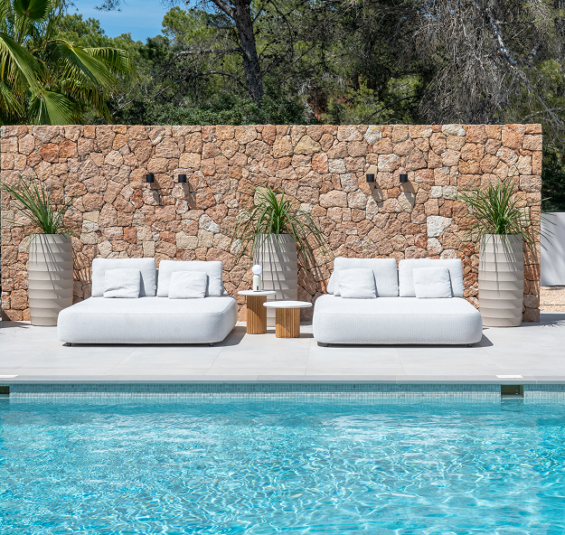 Two comfortable beige lounge beds in front of swimming pool