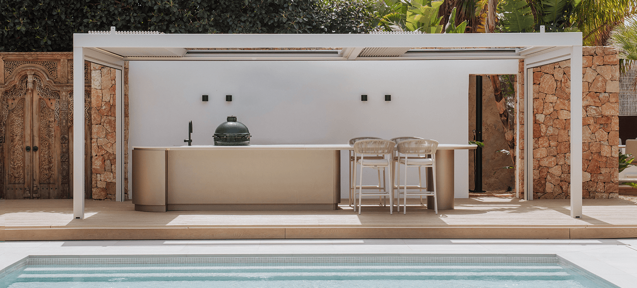 Luxury outdoor kitchen with Big Green Egg and a bar, in front of a swimming pool