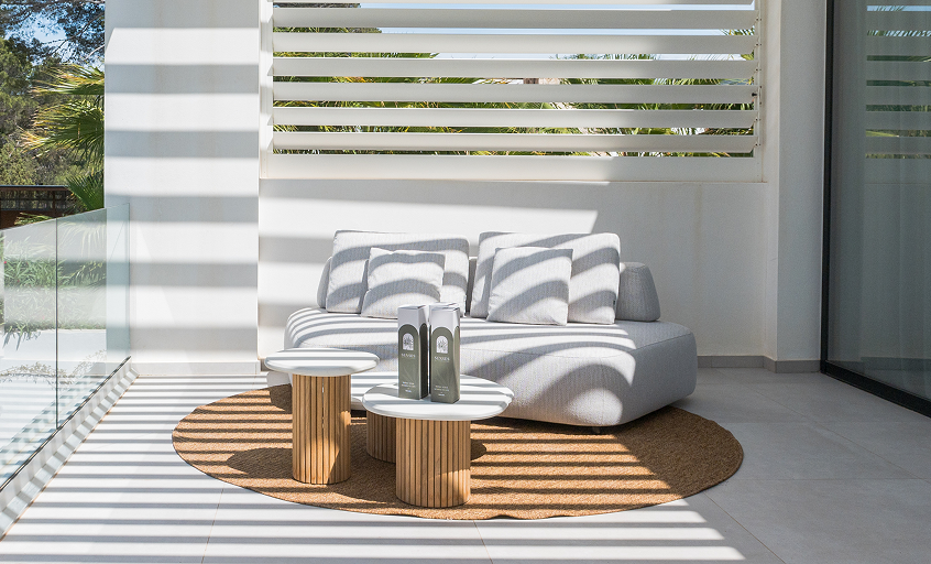 Beige outdoor lounge sofa on balcony with outdoor rug and coffee tables.