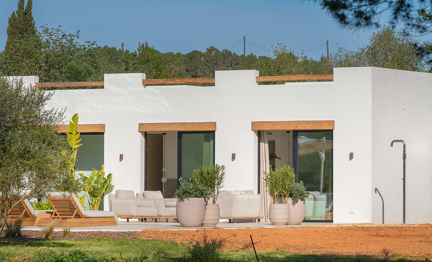 Luxury white villa with styled outdoor area with furniture, plants and a outdoor shower
