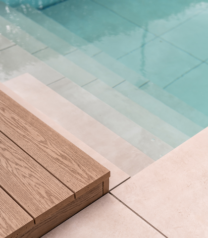 Close-up of pool steps with wooden deck and natural stone paving