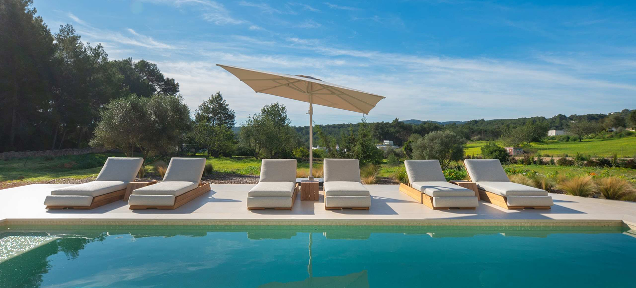 Six luxury sun beds with comfortable loungers and a parasol in front of swimming pool