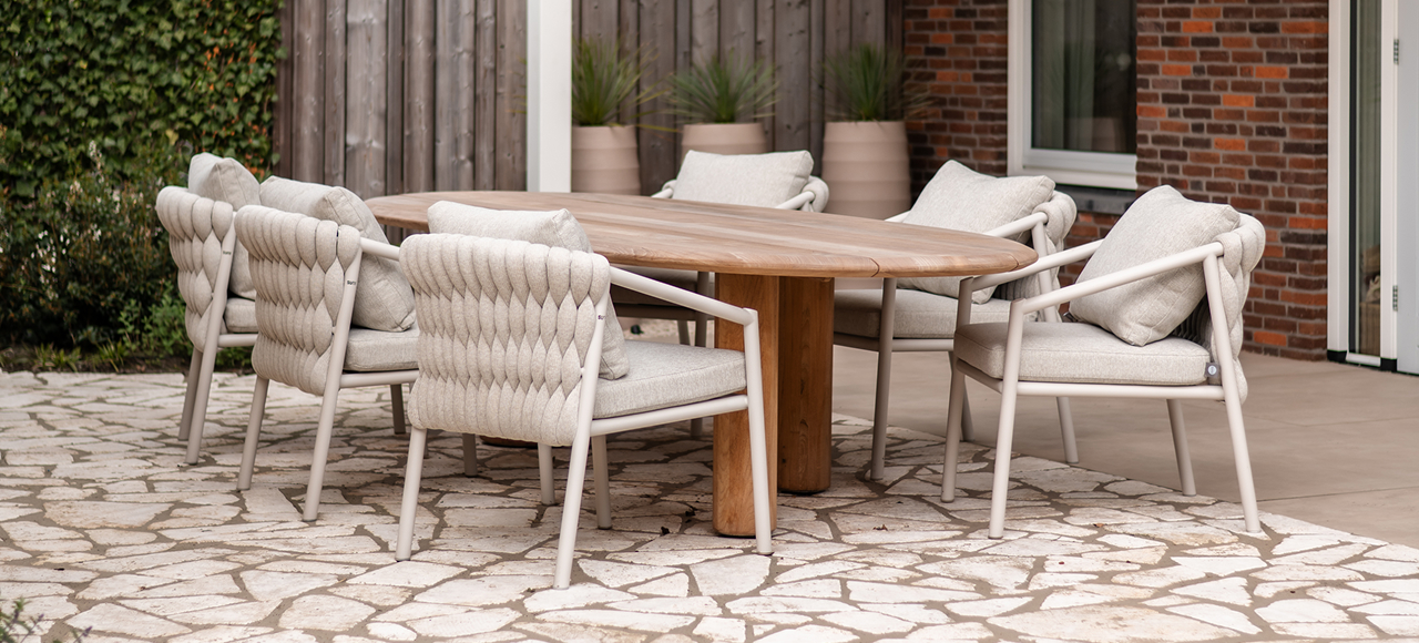 Wooden outdoor dining table with woven beige chairs with comfortable pillows