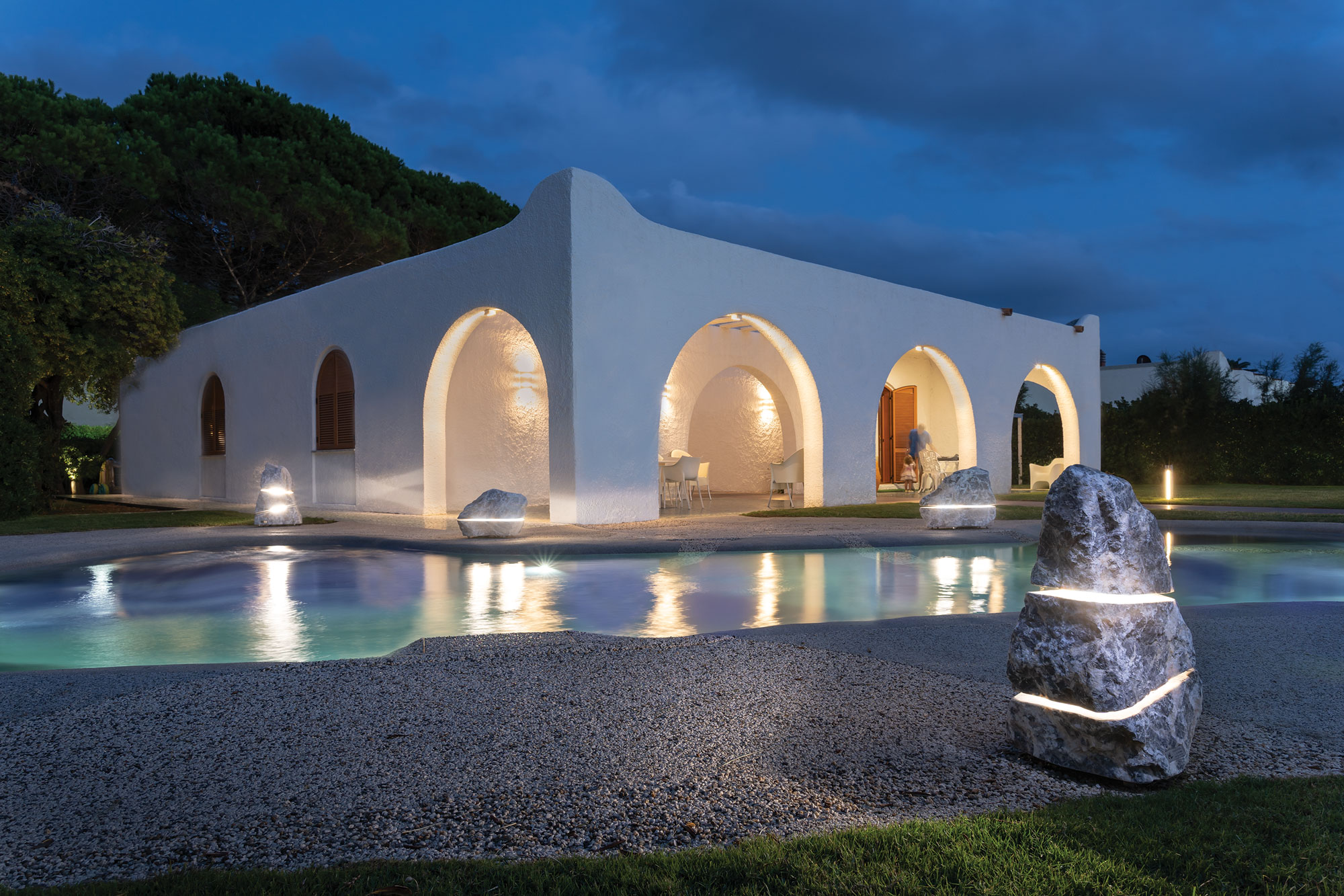 Luxury villa at night with illuminated stone lighting around the pool.