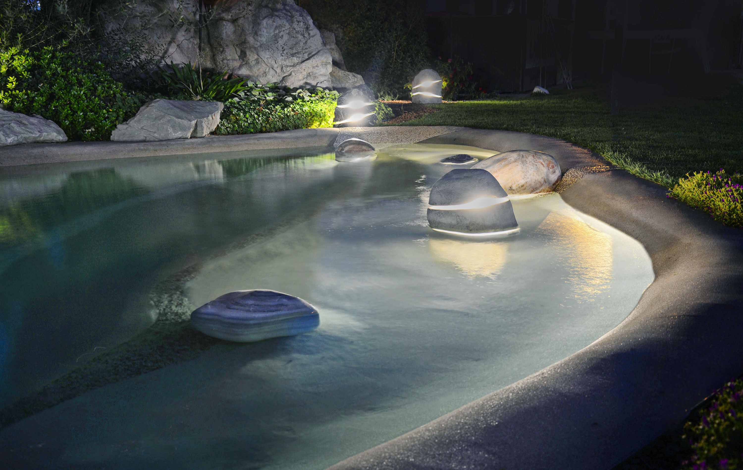 Menhir pool lights illuminating a natural swimming pool at night