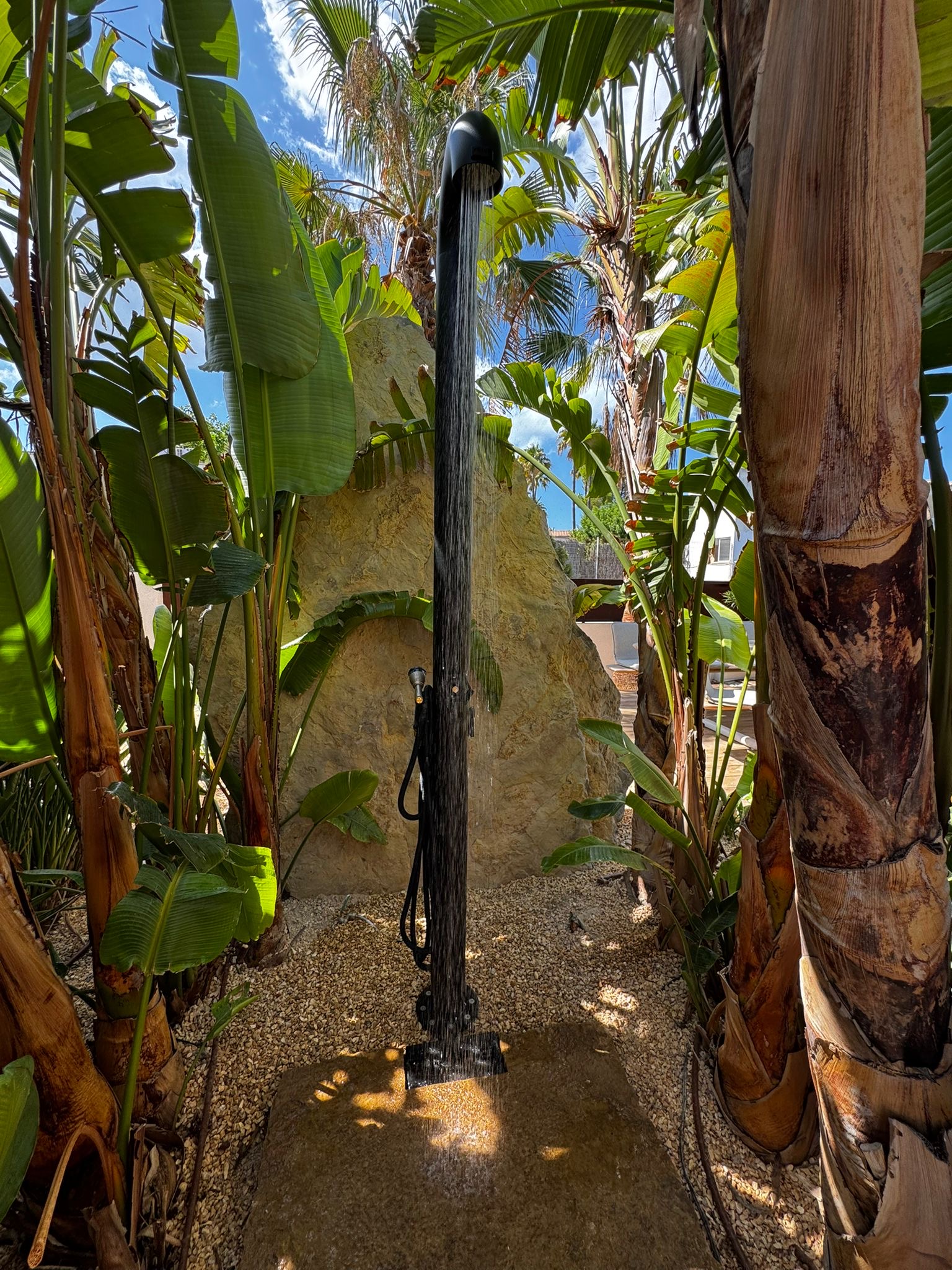 Black FRISS outdoor shower with water stream among tropical palm trees