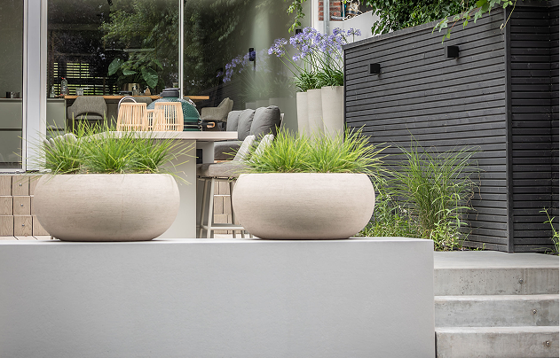 Modern city garden with round planters and dining table