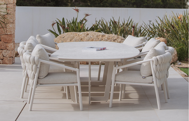 Round outdoor dining table with comfortable upholstered chairs in a modern garden.